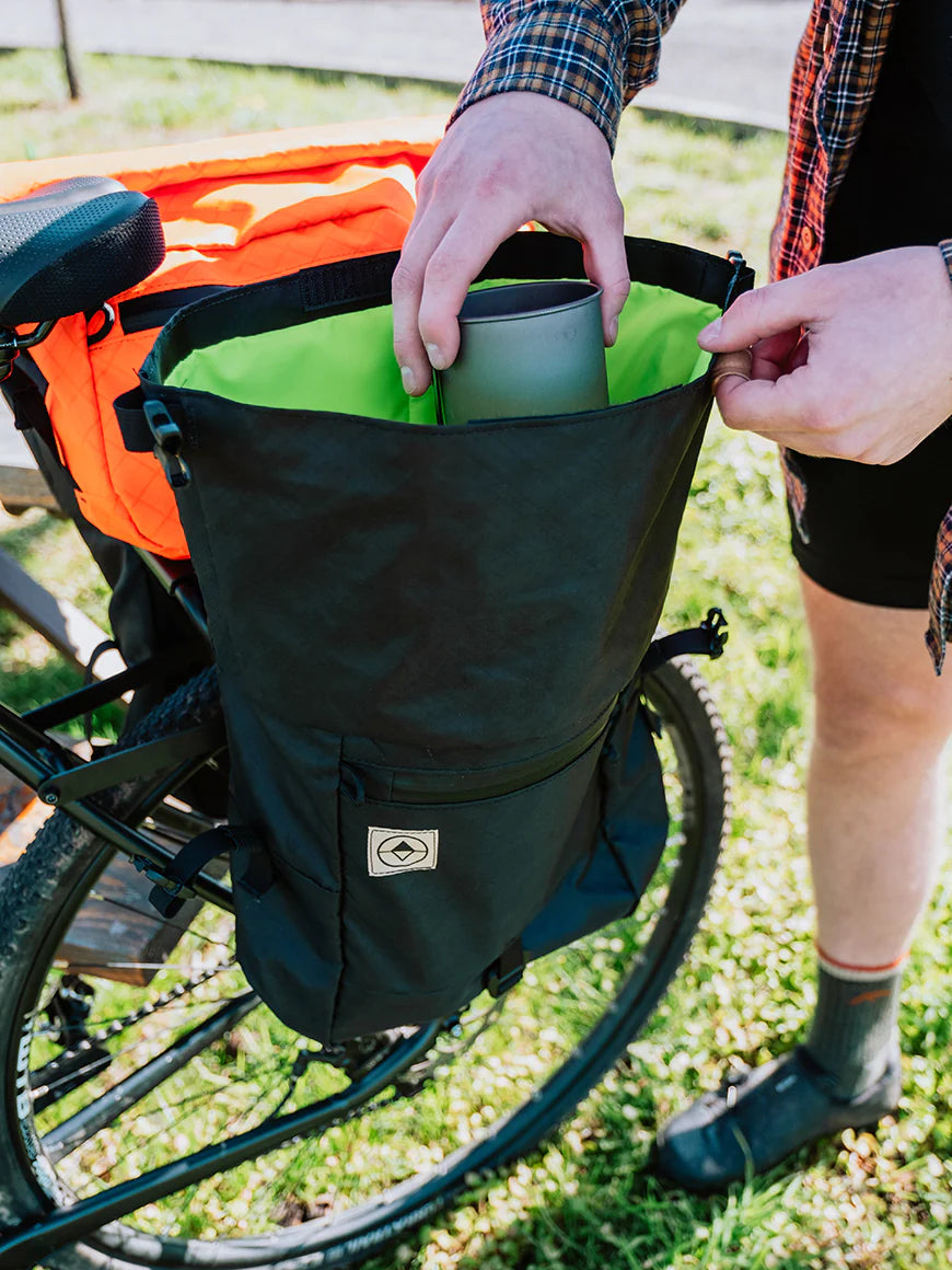 Cyclist packing a black Adventure Macro Pannier for a trip. North St Bags all-groups