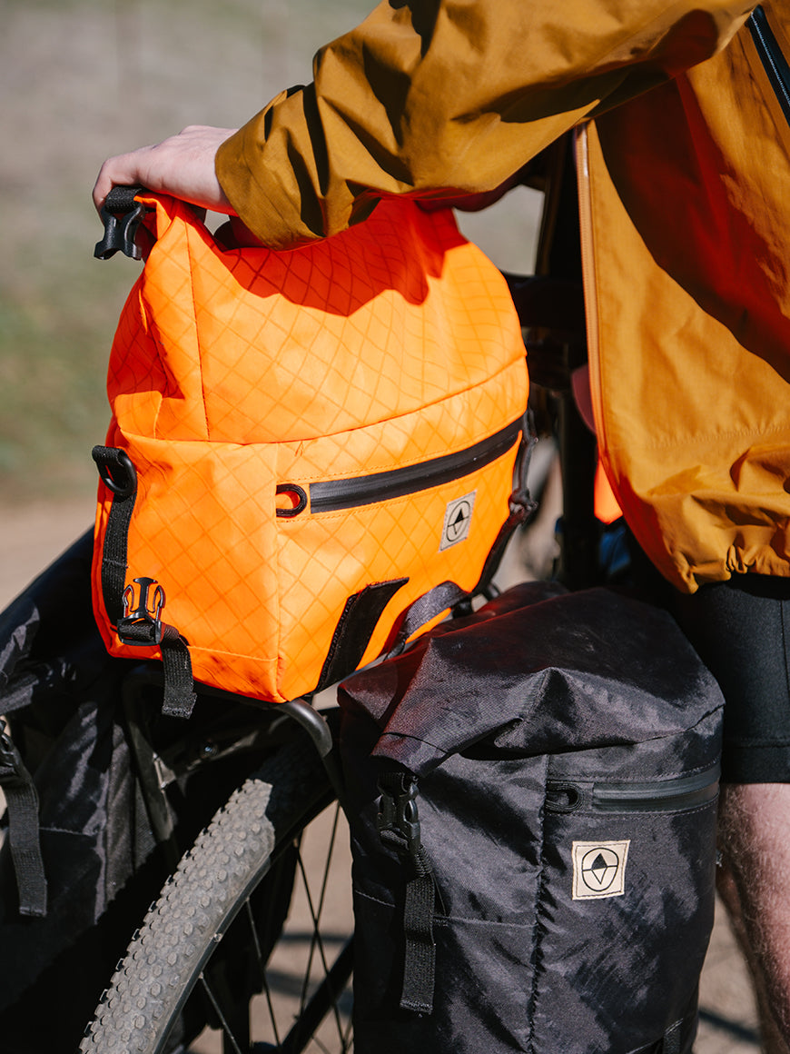 Man securing a Roll-Top Trunk Bag on his gravel bike- North St. Bags all-groups