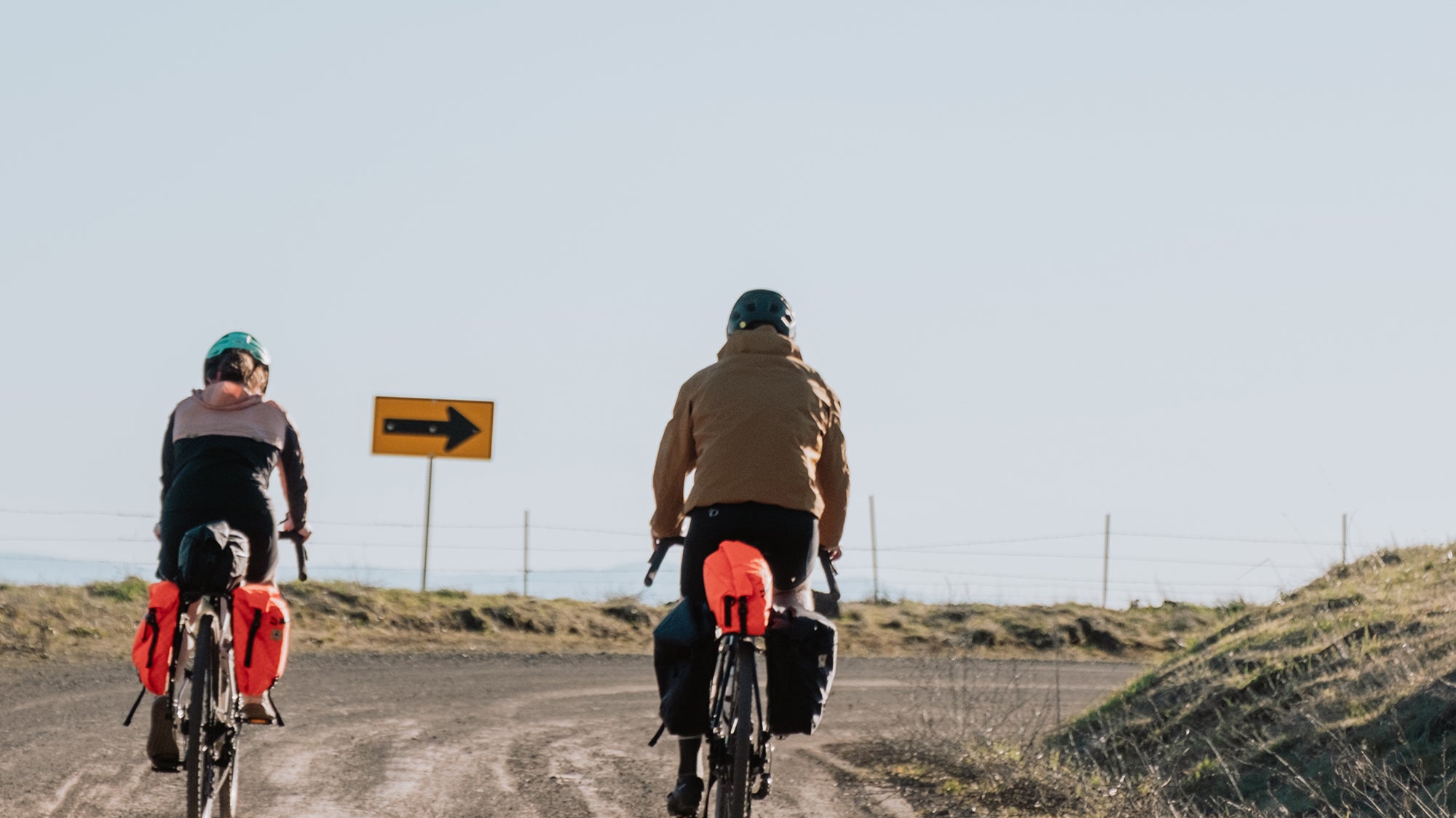 two cyclists riding on a gravel road with bikepacking bags