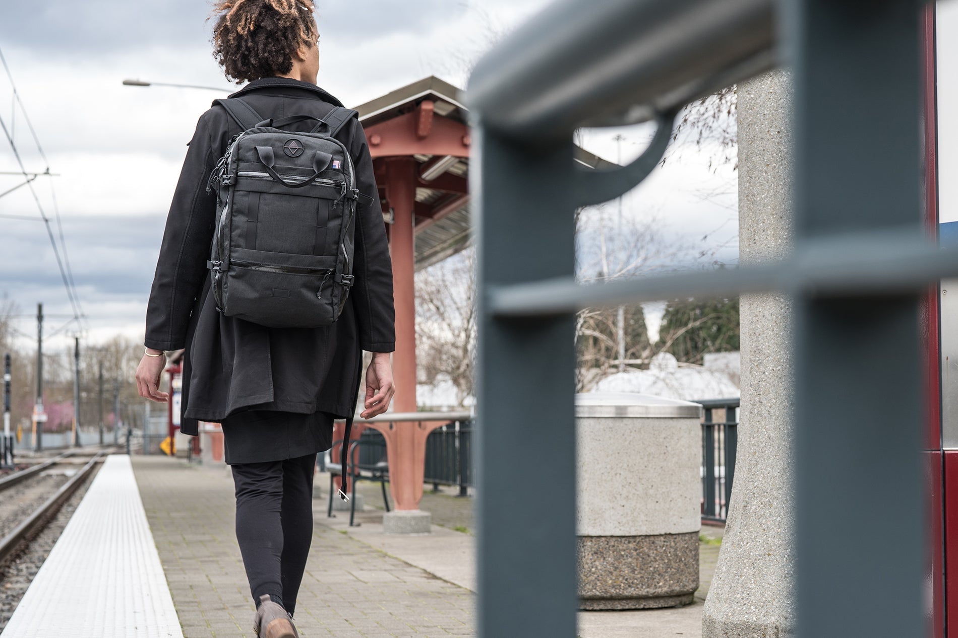 Woman wearing travel backpack walking along a train platform. | North St Bags