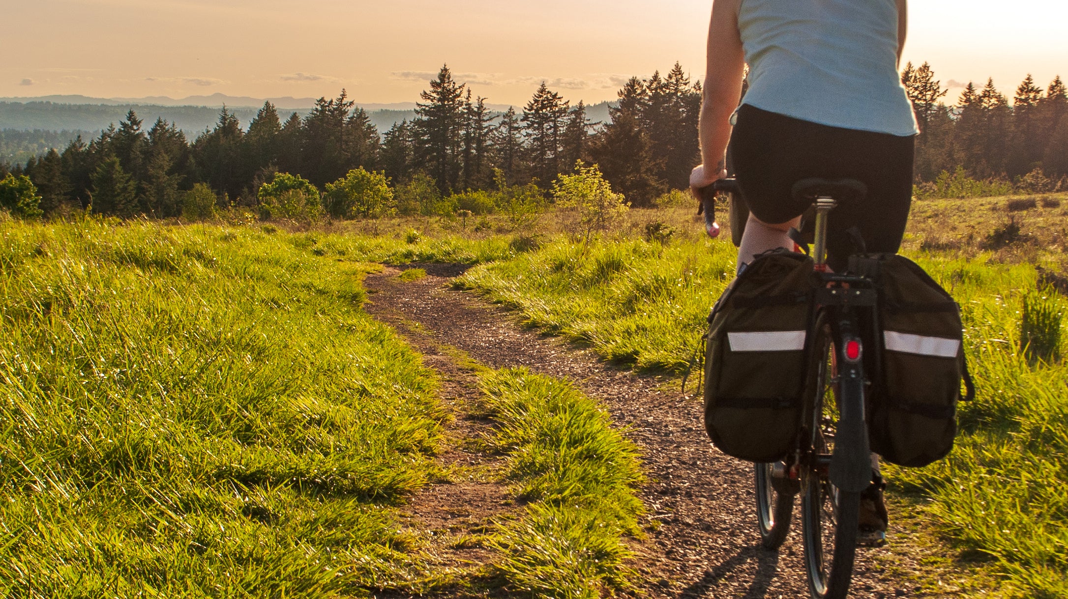 woman biking along a dirt path at sunset