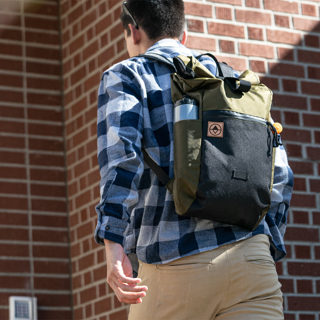 Man walking into a building wearing a daypack.