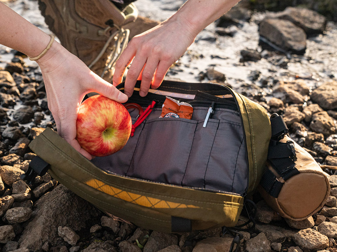 Pioneer 12 Pack on a rocky trail being loaded with snacks.- North St. Bags all-groups