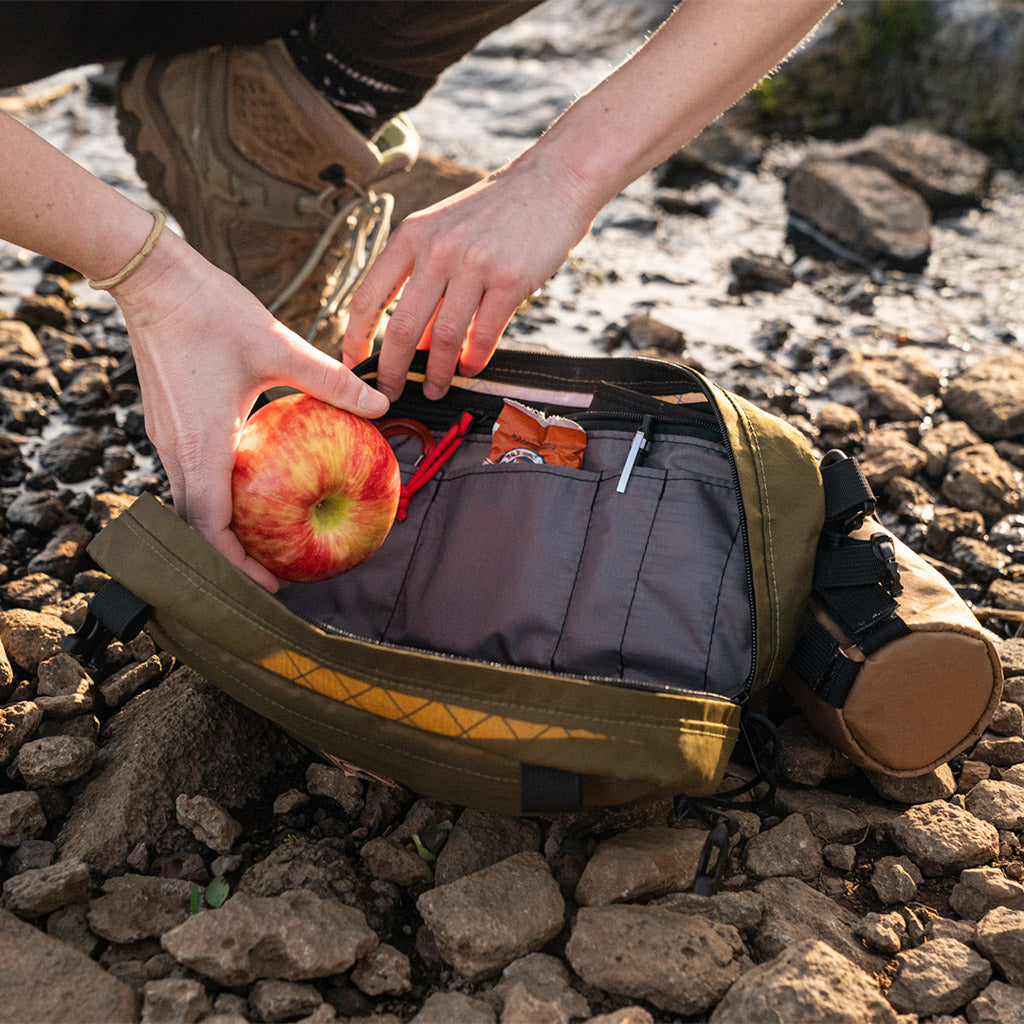 Person packing a Pioneer 12 Pack with snacks on a rocky trail - all-groups