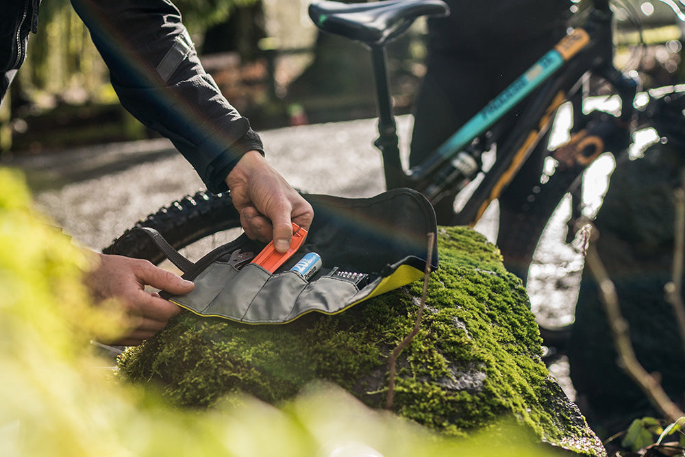 Man with mountain bike grabbing a tool out of his tool roll. - North St. Bags all-groups