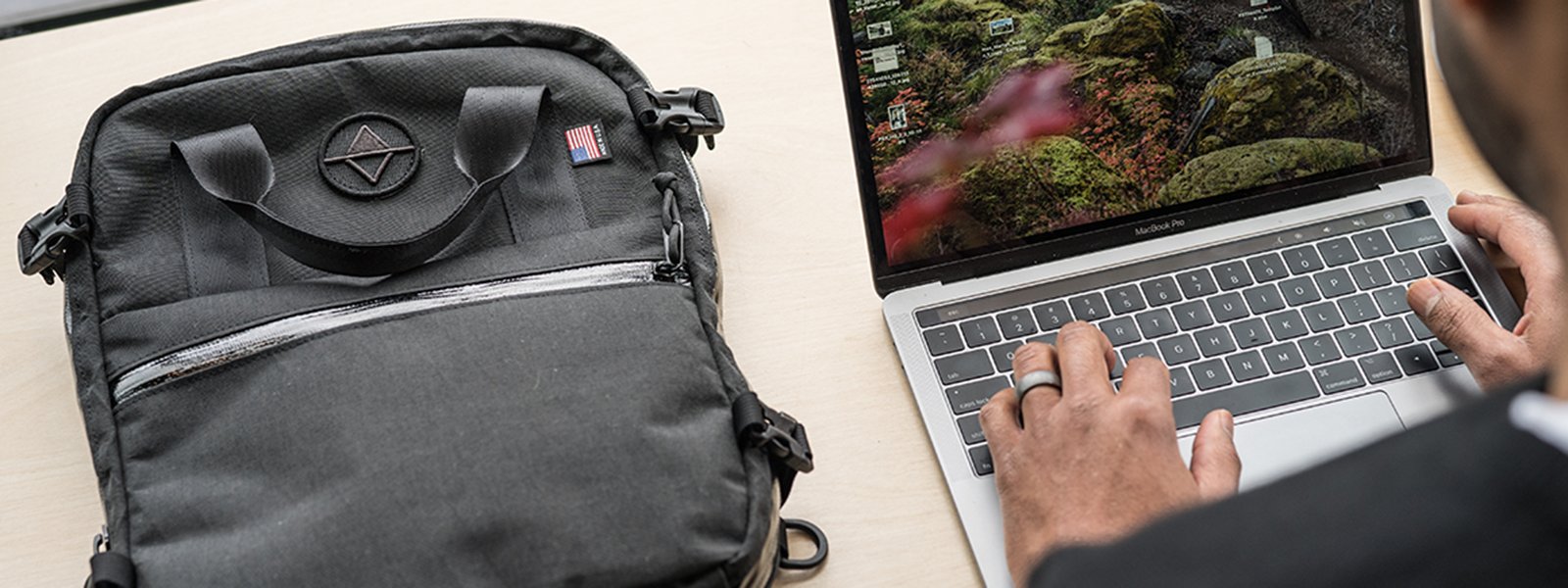 A man using a laptop with a laptop bag nearby.  | North St Bags