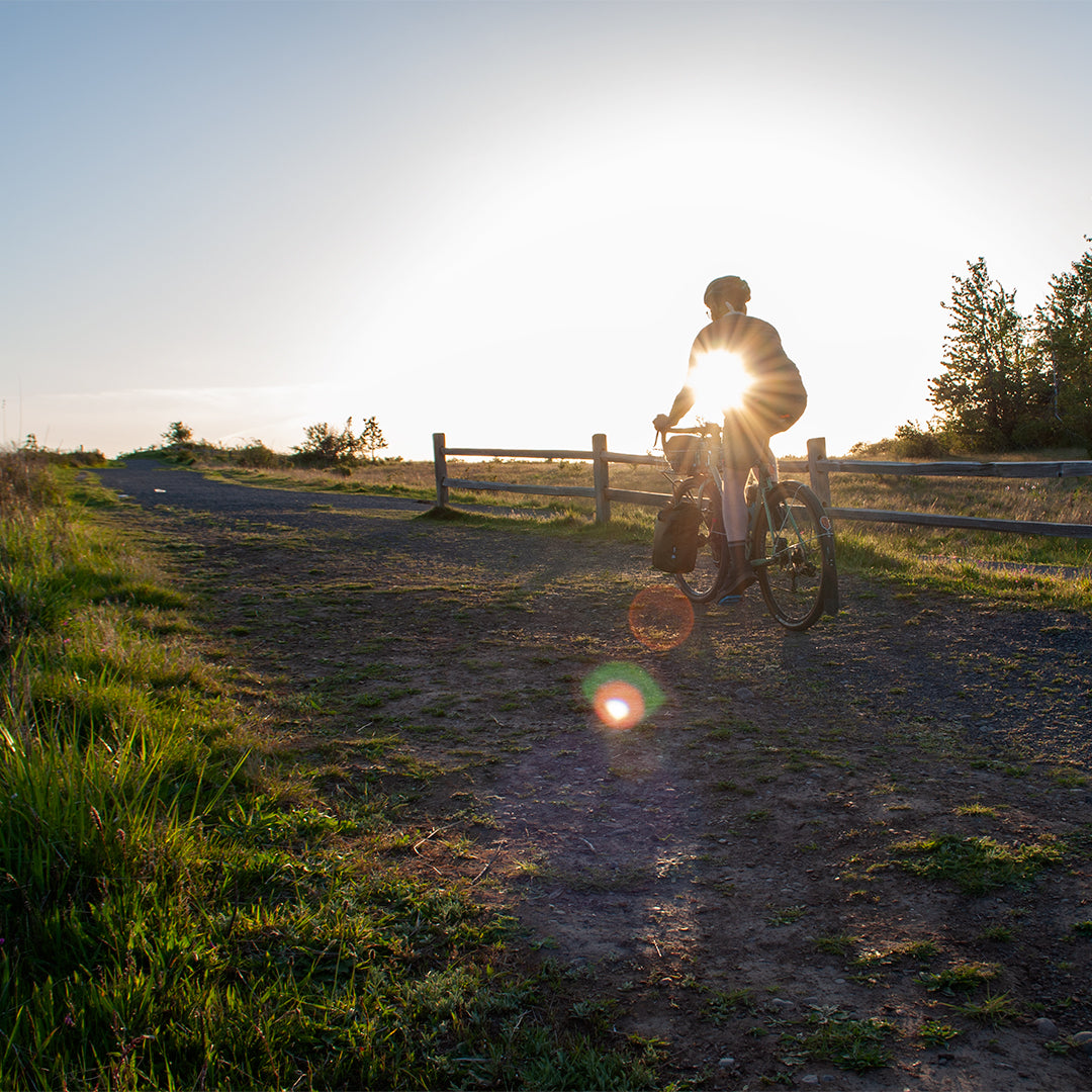 Cyclist riding at sunset on hillside with pannier - North St. Bags all-groups