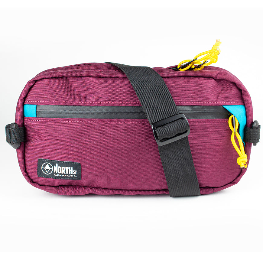 front view of sling pack by North St in burgundy and teal