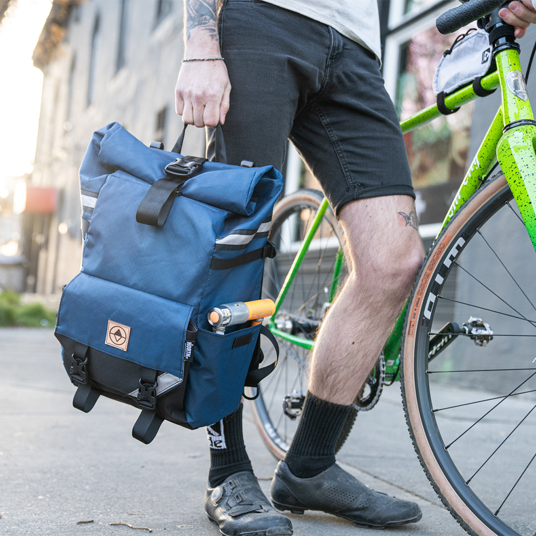 Man carrying Woodward Backpack Pannier by the grab handle. - North St. Bags all-groups