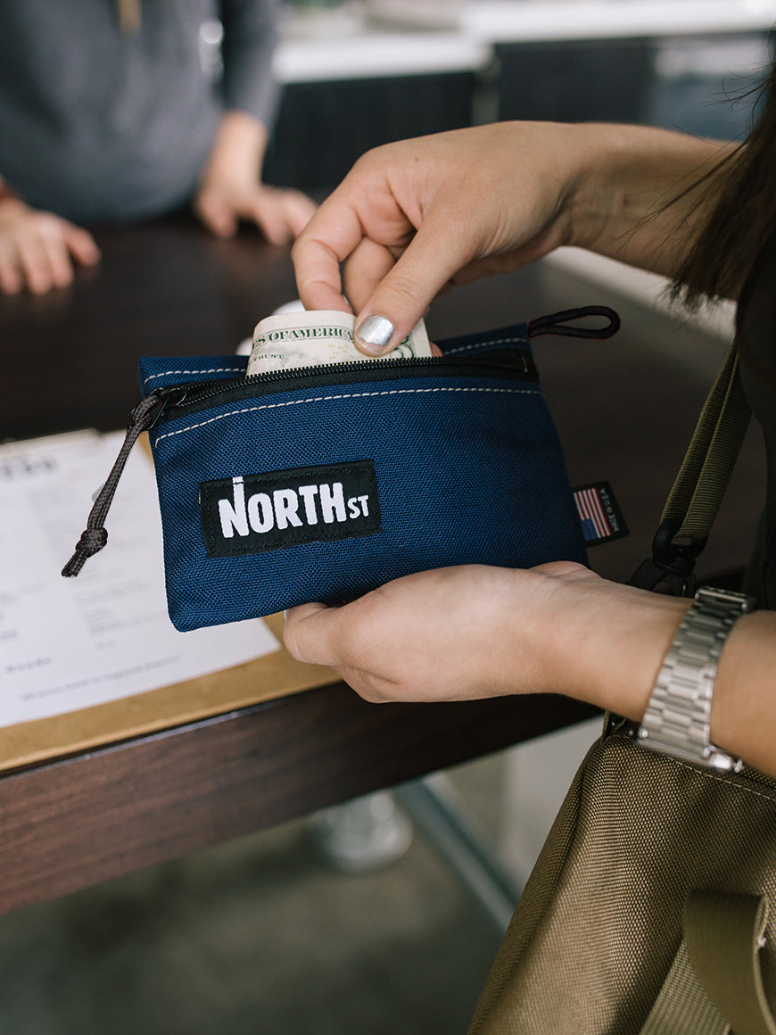 Woman getting cash out of a pouch at a coffee bar counter. - North St. Bags all-groups