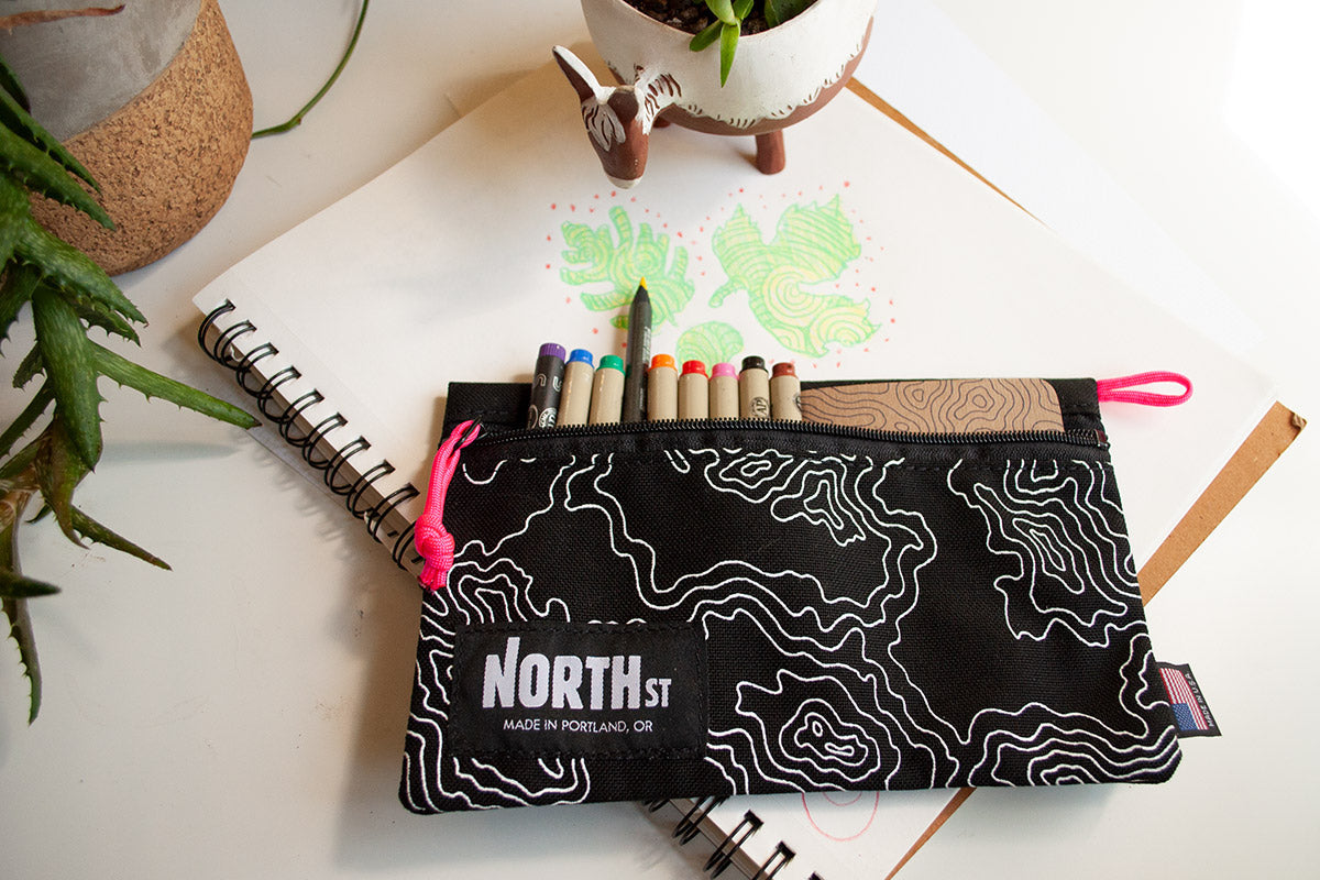 artist's sketchbook with a North St pouch filled with pencils and markers