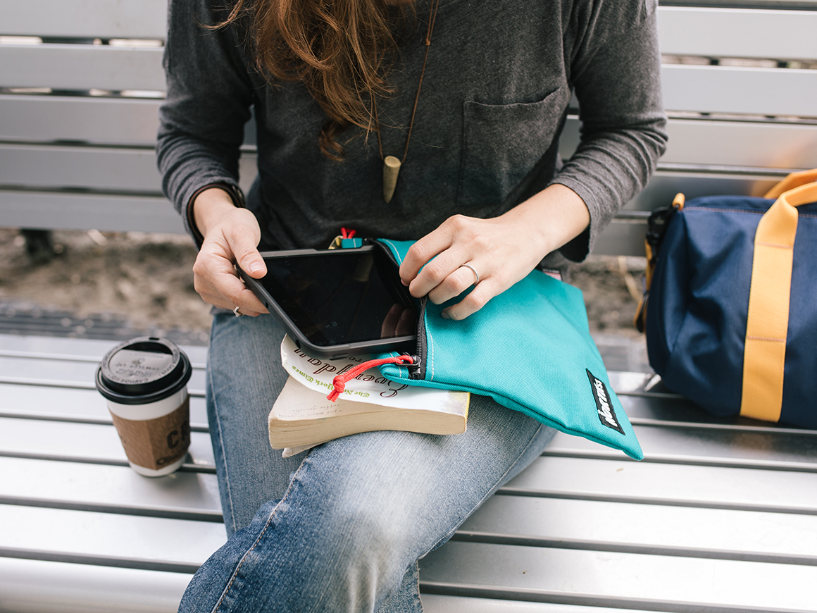 woman on a coffee break on a park bench with a book, ipad and North St pouch